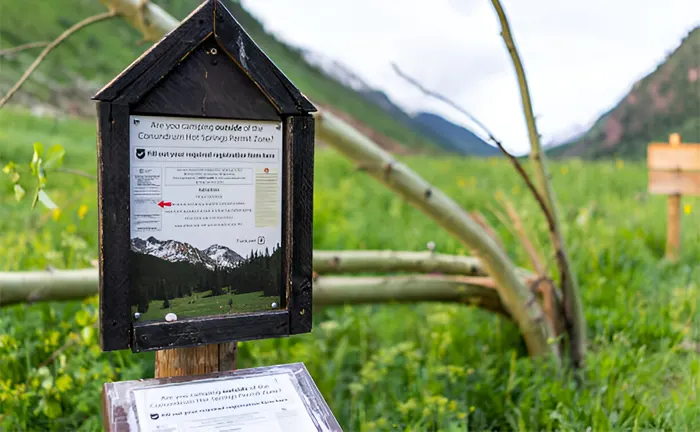 Information board in a green, mountainous area, highlighting sustainable logging practices.
