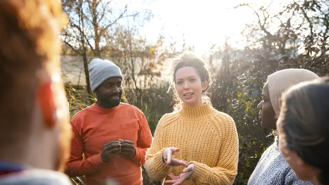 A group of people engaged in discussion outdoors, illustrating community involvement and education in forest conservation.