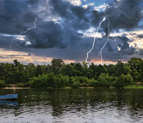 Lightning strikes over a forest and lake, illustrating natural causes of forest fires