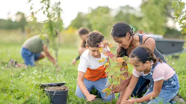 Children and adults planting trees together, highlighting community involvement and education in environmental conservation.