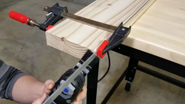 Dremel tool being used to cut through a clamped wooden plank.