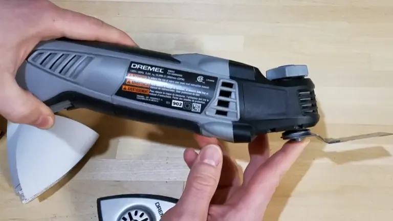Person holding a gray Dremel oscillating tool with a blade attachment.