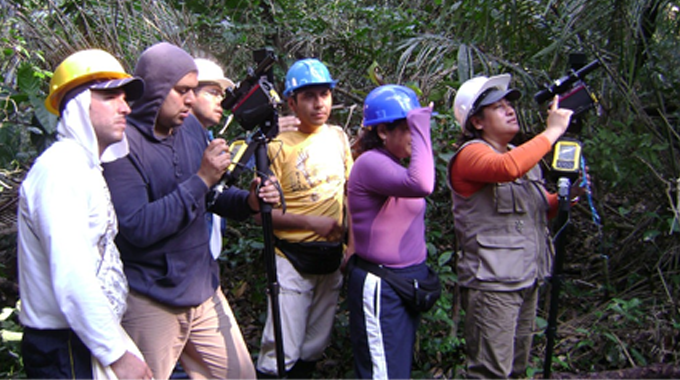 A group of field researchers wearing helmets and outdoor gear, using various instruments and equipment to collect data in a dense forest environment, illustrating hands-on forest management and research activities.