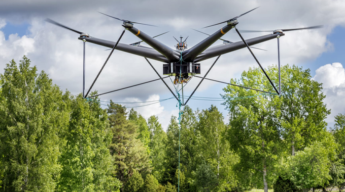 "Large drone equipped with multiple rotors hovering above a forested area, demonstrating its use in forestry management and environmental monitoring."