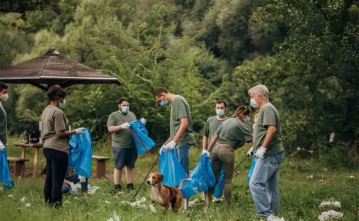 Group of volunteers wearing masks and collecting litter in a forest to promote a healthier ecosystem.