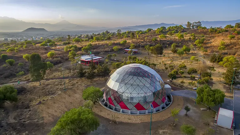 Urban ecosystem restoration with a geodesic dome and surrounding greenery.