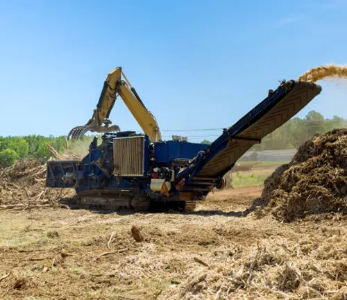 Chipper machine converting tree limbs and wood waste into small chips, maximizing resource use in forestry operations.