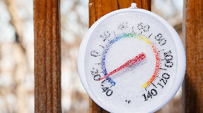 "A close-up of a frosty outdoor thermometer showing sub-zero temperatures, attached to a wooden surface."