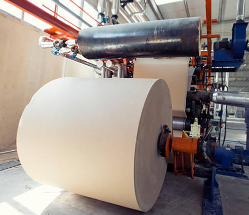 A large roll of paper is processed on an industrial machine, highlighting a key stage in the manufacturing process within the pulp and paper industry.