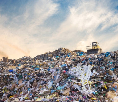 A large landfill site with piles of mixed waste under a partly cloudy sky, highlighting the challenges of waste management and the environmental impact of pollution.