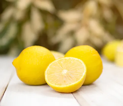 Whole and halved lemons on a table outdoors.