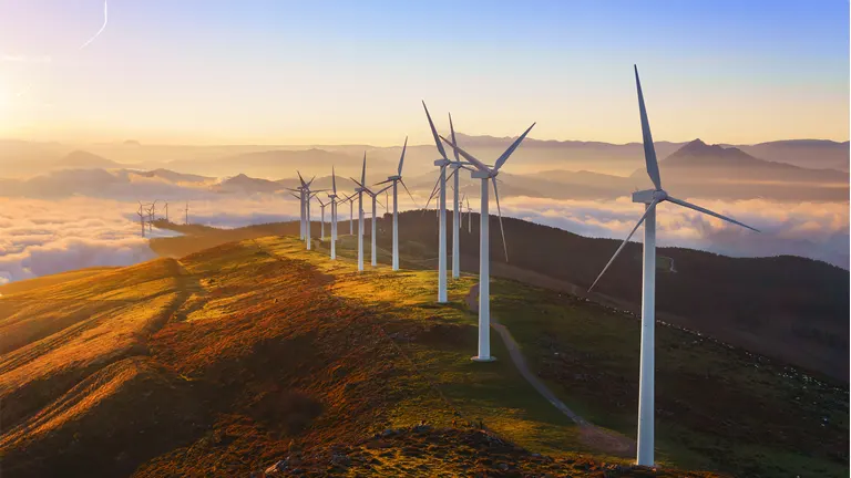 Wind turbines on a hilly landscape, symbolizing renewable energy integration in sustainable timber industry practices.