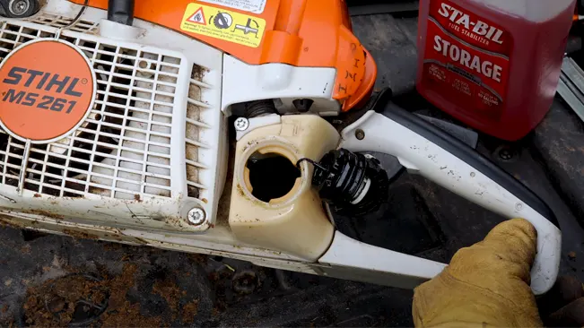 Close-up of a Stihl MS261 chainsaw with an open fuel cap and a fuel stabilizer nearby