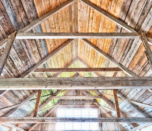 Interior view of a rustic wooden ceiling with exposed beams made from reclaimed wood.