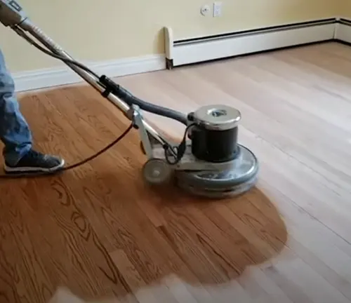 Polishing hardwood floors with a floor buffer to restore shine and smoothness.