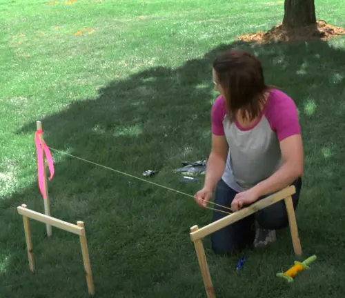 Person measuring and marking a yard with string for a fence installation.