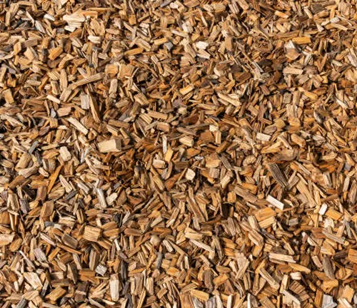 A large pile of wood mulch, commonly used as landscaping material for gardens.