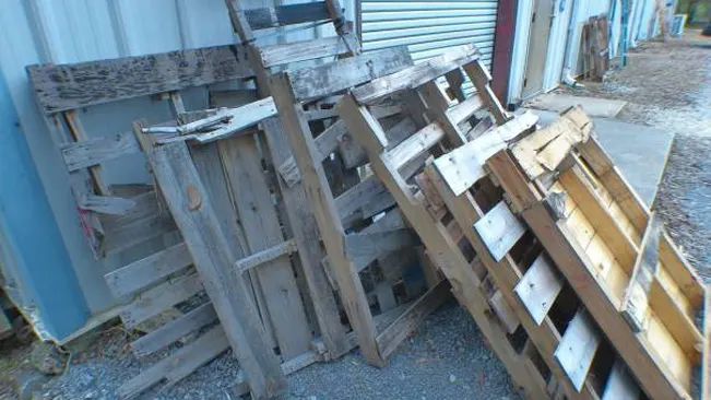 Weathered wooden pallets leaning against a building, ready for repurposing or recycling.