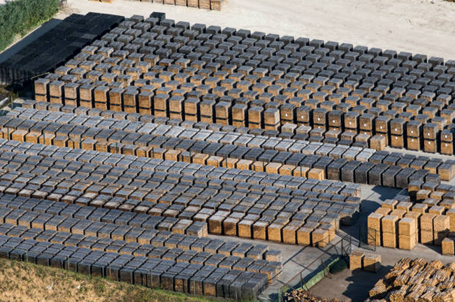 an organized outdoor storage facility with numerous stacks of timber crates arranged in neat rows. The crates are uniformly wrapped, indicating readiness for shipment.