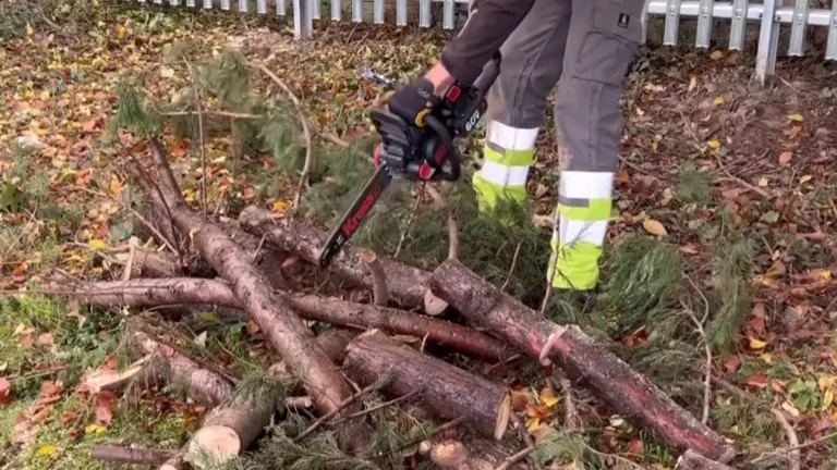 Worker using Kress Commercial 60V 14-inch top-handle chainsaw to cut small logs, showcasing its power and handling in fieldwork.