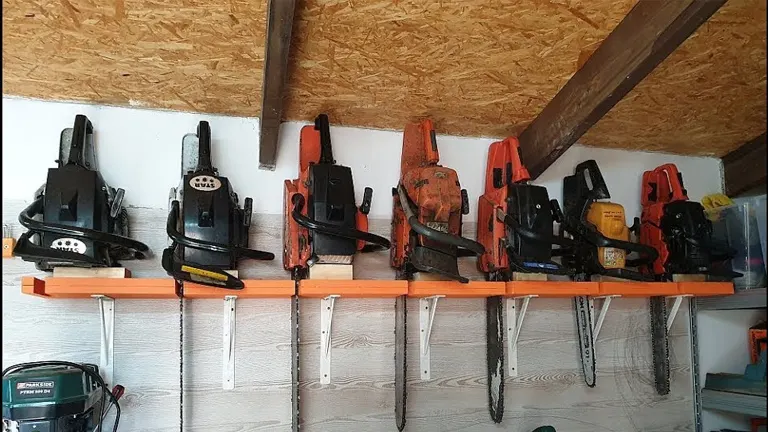 A row of chainsaws neatly stored on a shelf in a garage or workshop, showcasing proper organization for storm cleanup tools.