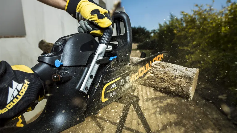 McCulloch CS 35S Petrol Chainsaw cutting through a log with sawdust flying.