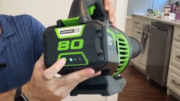 Person holding the Greenworks Pro 80V leaf blower, showing its battery pack with LED charge indicator.