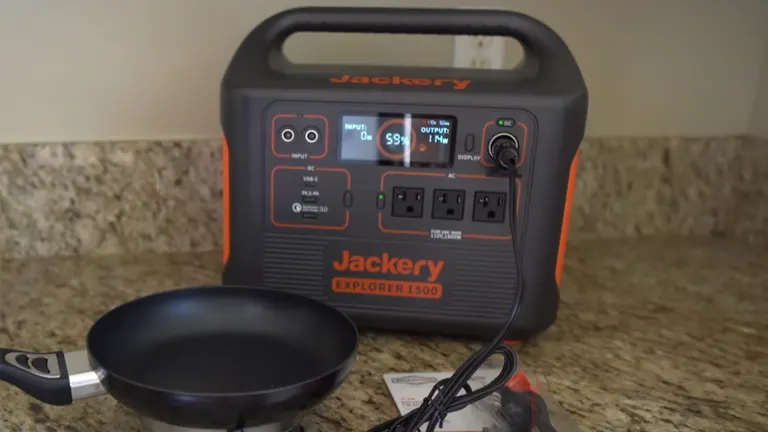 Jackery Explorer 1500 solar generator on a kitchen counter, powering a small frying pan, with a visible display showing power output.