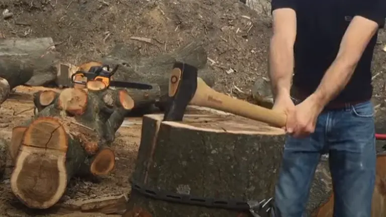 Person using a splitting axe on a large tree stump