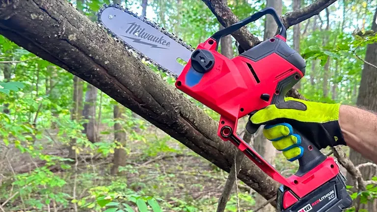 Person using a Milwaukee M18 FUEL mini chainsaw to prune a tree branch in a forest setting.