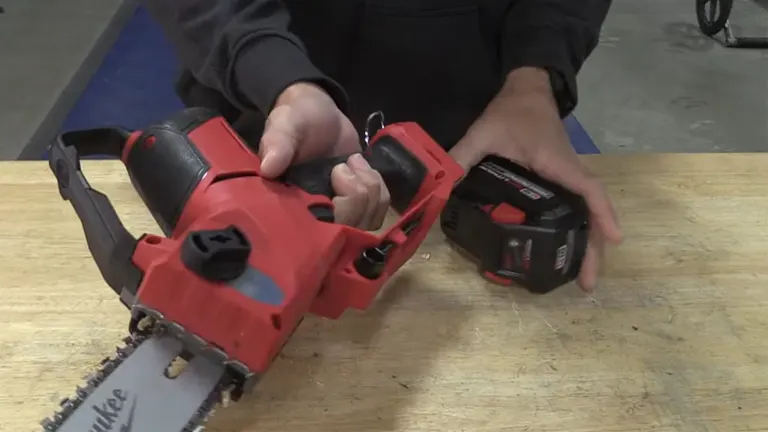 Person preparing to attach the battery to a Milwaukee M18 FUEL mini chainsaw on a workbench.