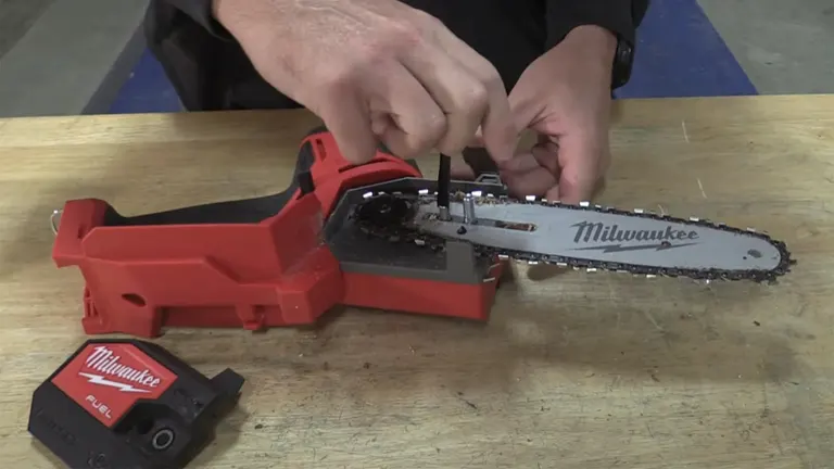 Person adjusting the chain tension of a Milwaukee M18 FUEL mini chainsaw with a wrench on a workbench.