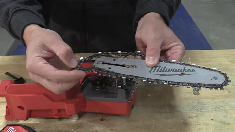 Person inspecting the chain and bar of a Milwaukee M18 FUEL mini chainsaw during maintenance on a workbench.