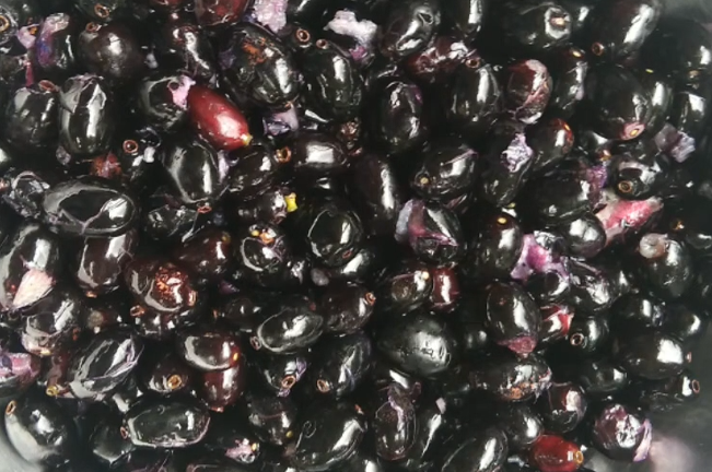 A close-up of many small, round, dark blue fruits piled together.