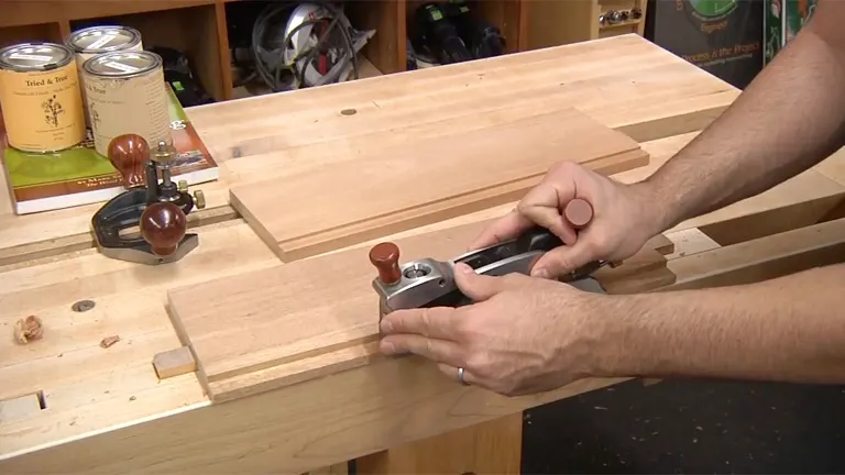 Woodworker using a hand plane to create a rabbet joint on a wood board.